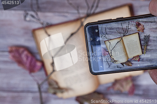 Image of Book And Autumn Leaves Through Smartphone