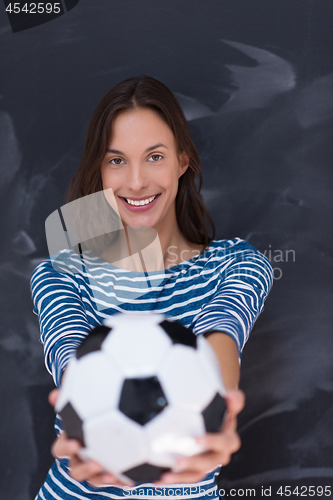 Image of woman holding a soccer ball in front of chalk drawing board