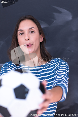 Image of woman holding a soccer ball in front of chalk drawing board