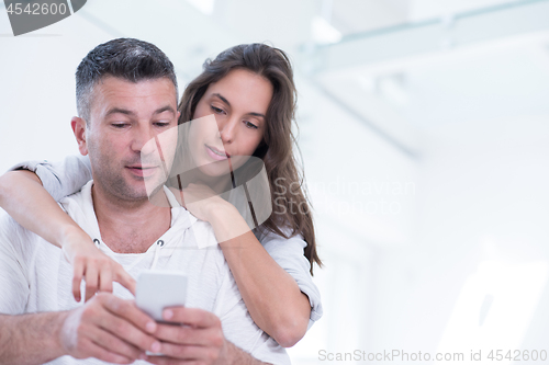 Image of happy couple using mobile phone at home