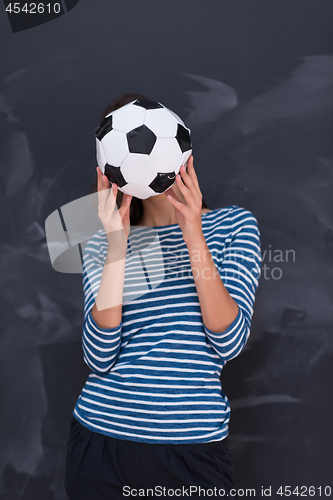 Image of woman holding a soccer ball in front of chalk drawing board