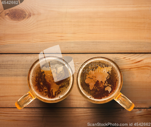 Image of world map silhouette on foam in beer glass on wooden table.