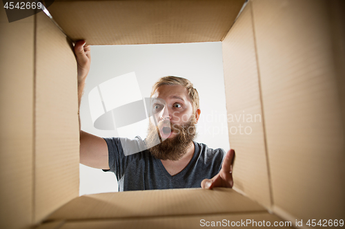 Image of Man unpacking and opening carton box and looking inside