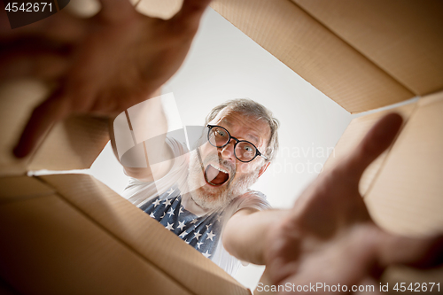 Image of Man unpacking and opening carton box and looking inside