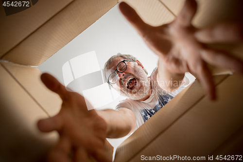 Image of Man unpacking and opening carton box and looking inside