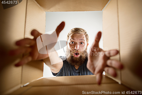 Image of Man unpacking and opening carton box and looking inside