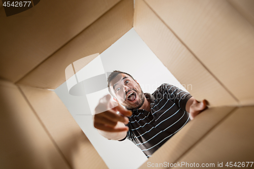 Image of Man smiling, unpacking and opening carton box and looking inside