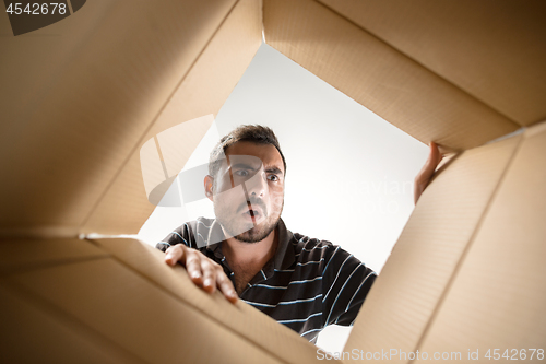 Image of Man unpacking and opening carton box and looking inside