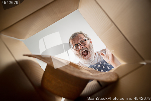 Image of Man unpacking and opening carton box and looking inside