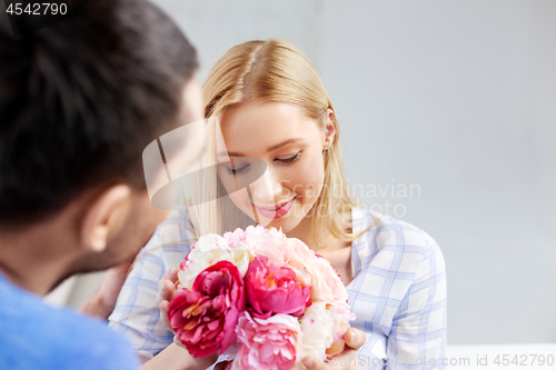 Image of happy couple with flowers at home