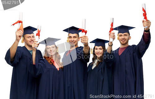 Image of graduates in mortar boards with diplomas