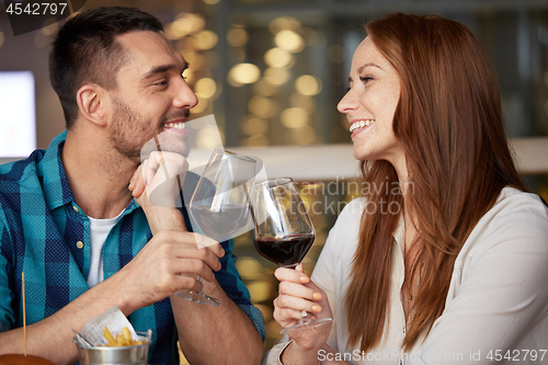 Image of happy couple drinking red wine at restaurant