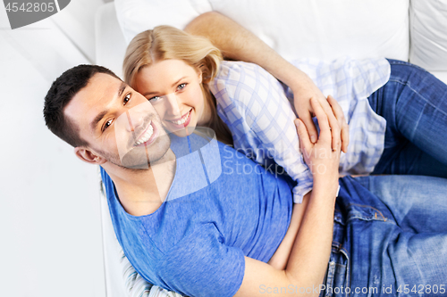 Image of happy couple sitting on sofa and hugging at home