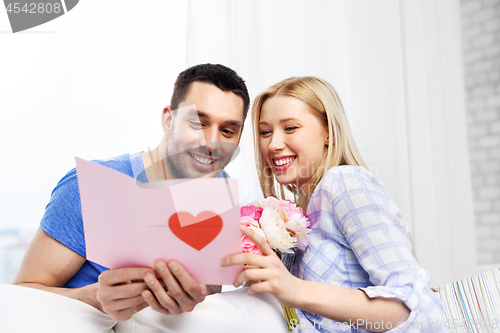 Image of happy couple with greeting card and flowers