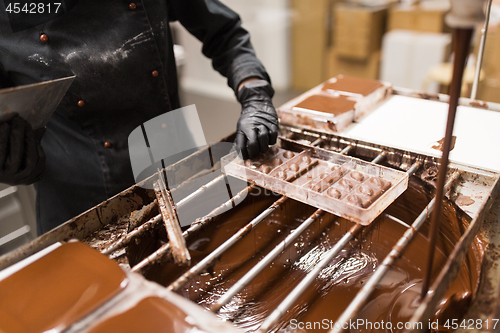 Image of confectioner removing excess chocolate from mold