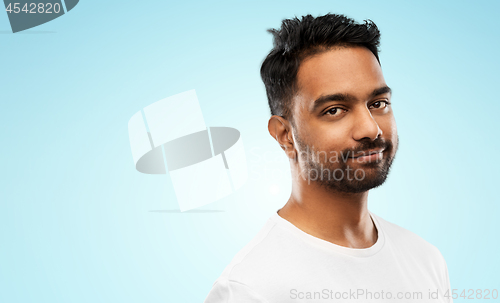 Image of smiling young indian man over blue background