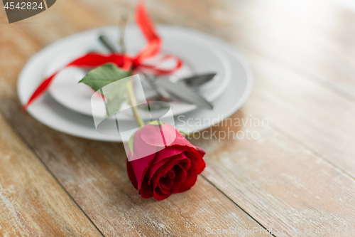 Image of close up of red rose flower on set of dishes