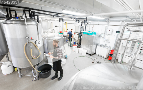 Image of man with clipboard at craft brewery or beer plant