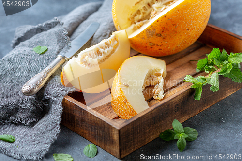 Image of Slices of ripe yellow melon in a wooden tray.