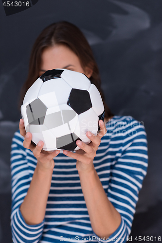 Image of woman holding a soccer ball in front of chalk drawing board