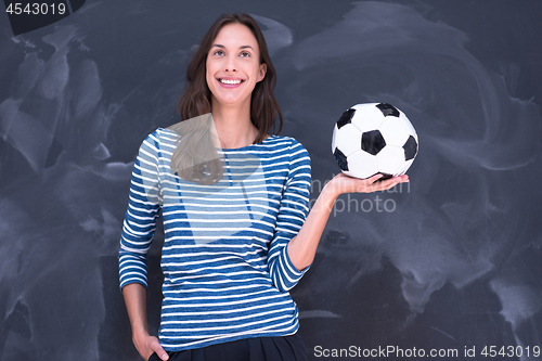 Image of woman holding a soccer ball in front of chalk drawing board