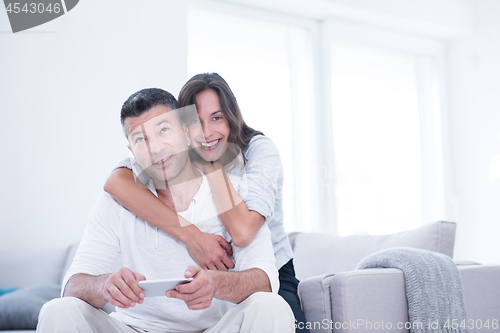 Image of happy couple using mobile phone at home