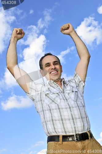 Image of Happy man raising hands in victory