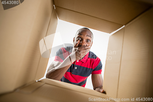 Image of Man unpacking and opening carton box and looking inside