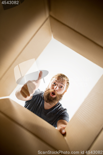 Image of Man unpacking and opening carton box and looking inside