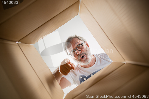 Image of Man unpacking and opening carton box and looking inside