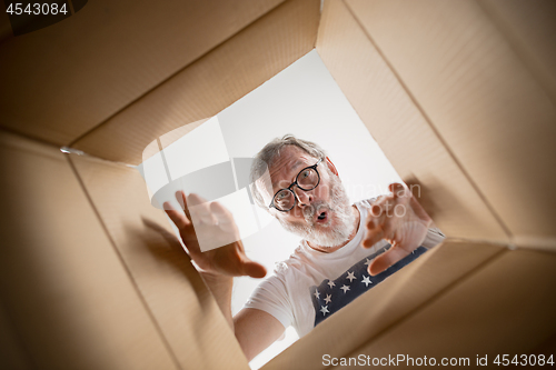 Image of Man unpacking and opening carton box and looking inside