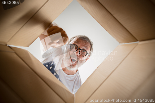 Image of Man unpacking and opening carton box and looking inside