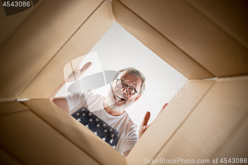 Image of Man unpacking and opening carton box and looking inside