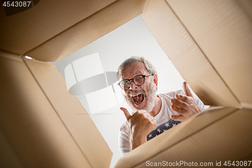 Image of Man unpacking and opening carton box and looking inside