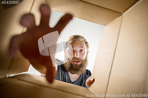 Image of Man unpacking and opening carton box and looking inside