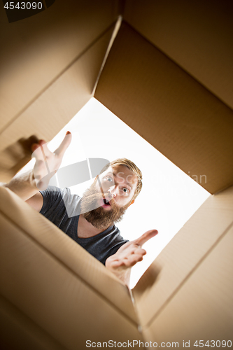 Image of Man unpacking and opening carton box and looking inside