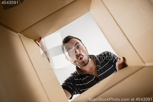 Image of Man unpacking and opening carton box and looking inside