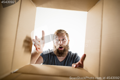 Image of Man unpacking and opening carton box and looking inside