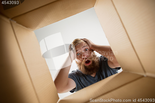 Image of Man unpacking and opening carton box and looking inside