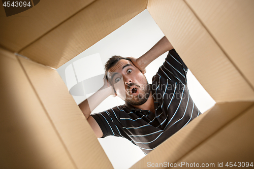 Image of Man unpacking and opening carton box and looking inside