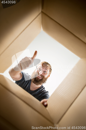 Image of Man unpacking and opening carton box and looking inside