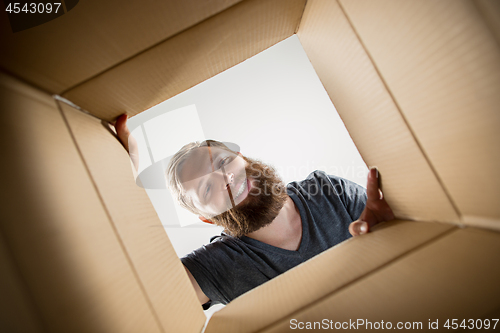 Image of Man unpacking and opening carton box and looking inside