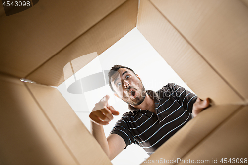 Image of Man unpacking and opening carton box and looking inside