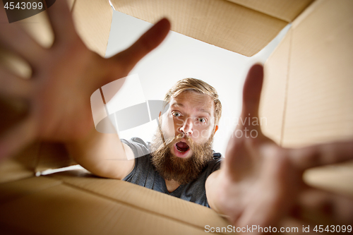 Image of Man unpacking and opening carton box and looking inside