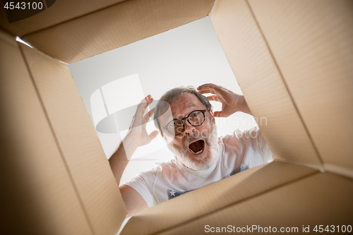 Image of Man unpacking and opening carton box and looking inside