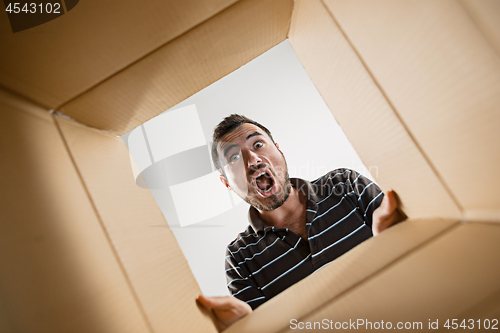 Image of Man unpacking and opening carton box and looking inside