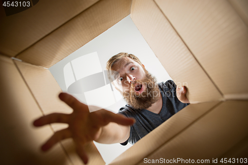 Image of Man unpacking and opening carton box and looking inside