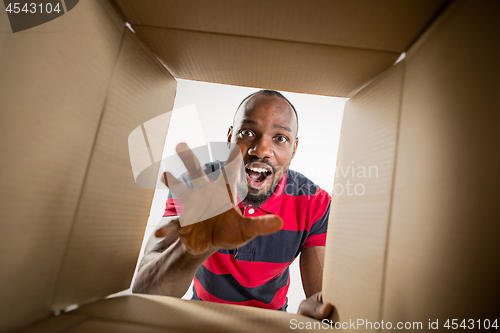 Image of Man unpacking and opening carton box and looking inside