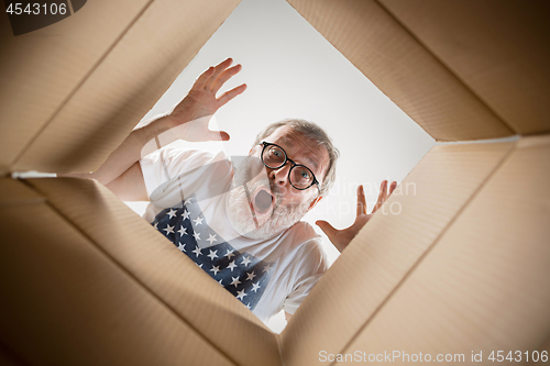 Image of Man unpacking and opening carton box and looking inside