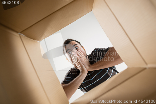 Image of Man unpacking and opening carton box and looking inside